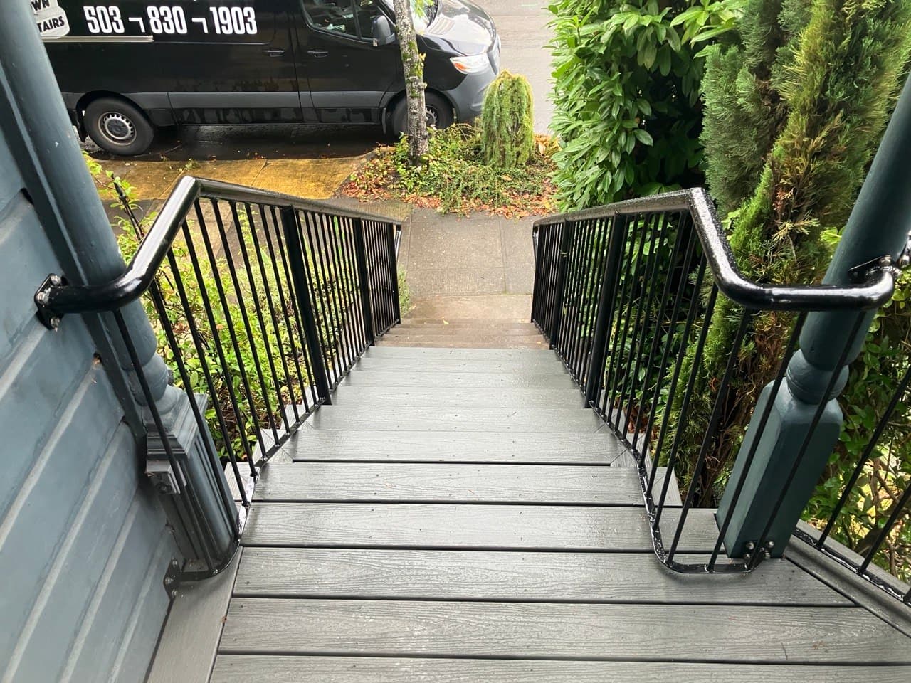 Black wrought-iron stair railings on composite front steps, Stumptown Stairs van at the curb — railing work in Portland, OR