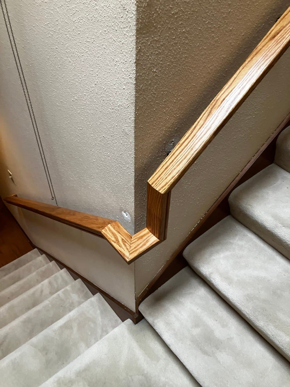 Oak handrail wall-return detail on a remodeled staircase in Portland