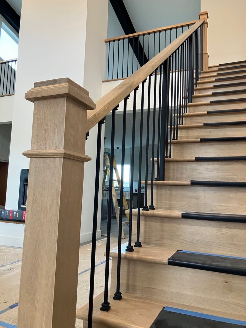 Custom white oak staircase with iron balusters and black tread accents in a newer Scappoose-area home