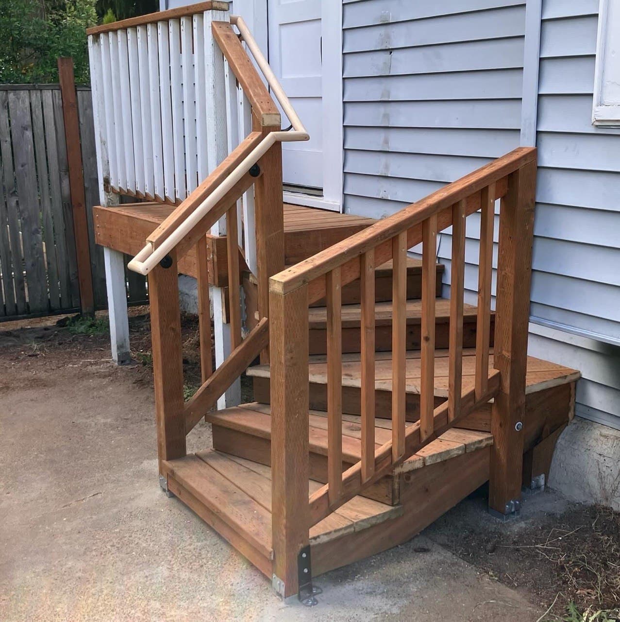 New cedar stair railing with wood balusters and round continuous handrail on exterior entry steps — built by Stumptown Stairs, Portland, OR