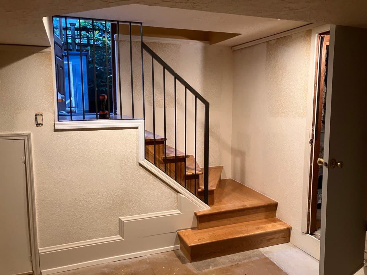 L-shaped white oak staircase with black steel railing at a basement entry, Portland, OR