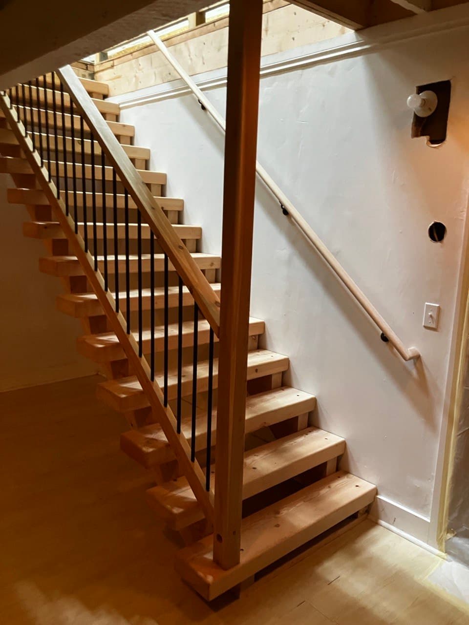 Open-riser fir staircase with black steel balusters, mid-build — Stumptown Stairs custom work, Portland, OR