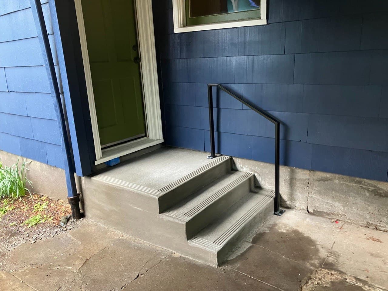 New concrete entry steps with safety-grooved nosings and a welded black steel handrail — poured and fabricated in-house by Stumptown Stairs, Portland, OR