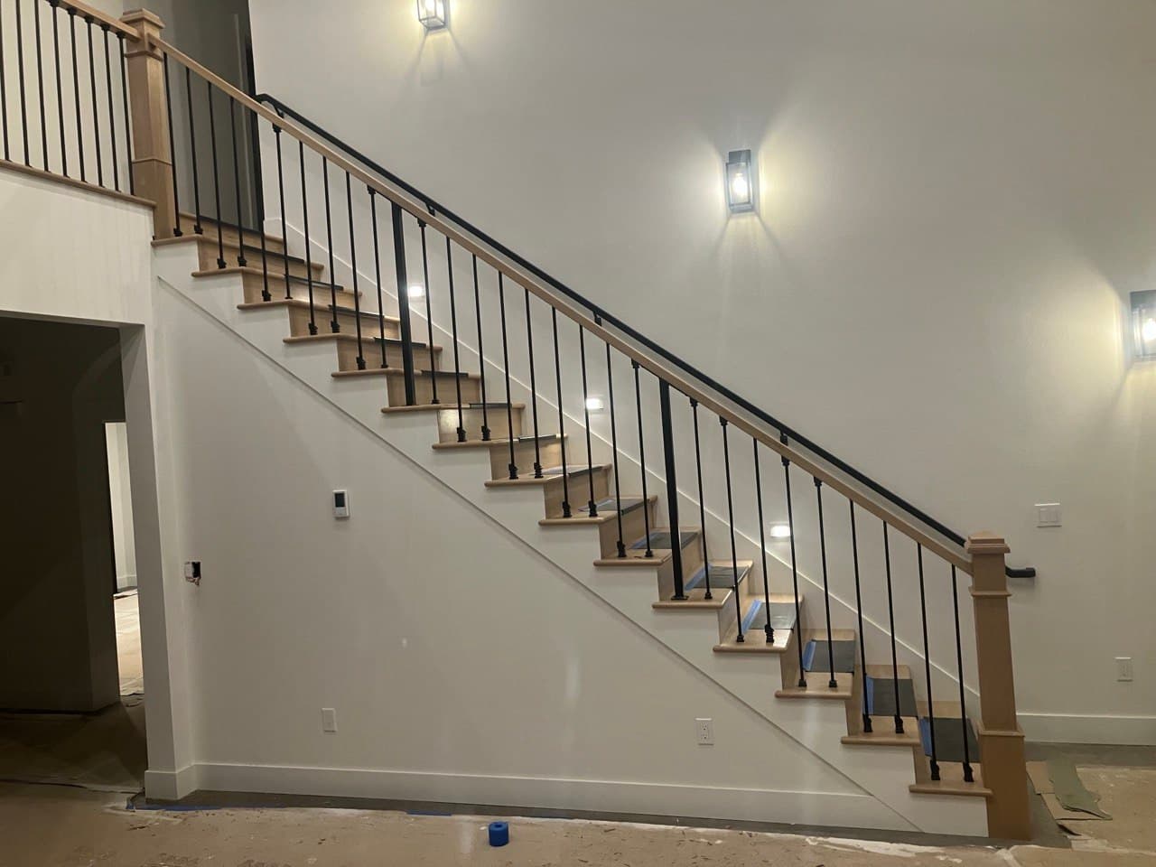 Full staircase remodel — white oak treads, black steel balusters, and wood handrail with new sconce lighting, by Stumptown Stairs, Portland, OR